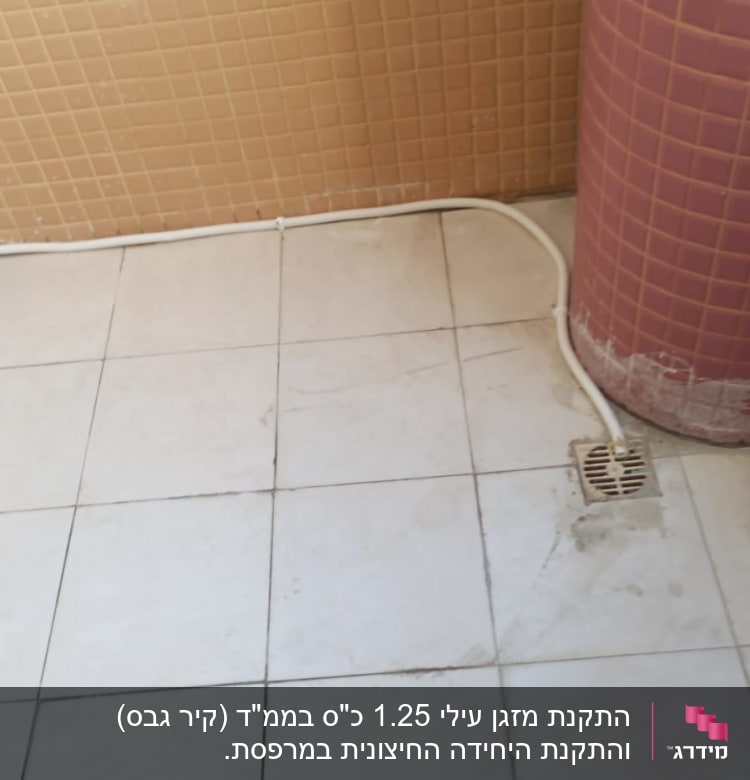צינור לבן מחובר לרצפה ליד ניקוז
